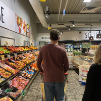 "Thilo beim Einkaufen im REWE vor der Obsttheke mit dem Einkaufswagen in der Hand."
