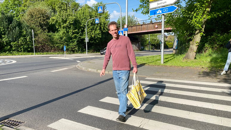 "Thilo mit einer Einkaufstasche auf einem Zebrastreifen"